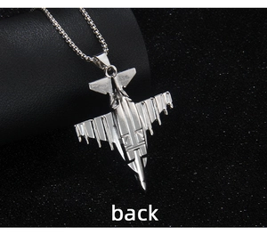 Macro detail of silver fighter jet pendant with polished box chain on black texture