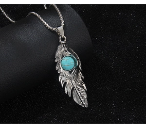 Détail macro du pendentif plume en argent antique avec incrustation de turquoise