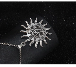 Macro shot of silver sun-shaped Eye of Horus pendant on black leather texture