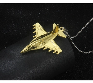 Detailed close-up of a gold fighter jet pendant with fine wings and cockpit textures
