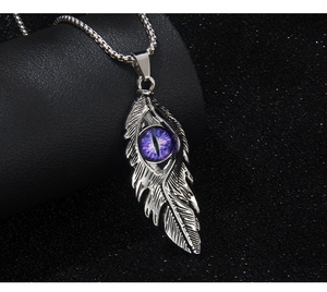 Gros plan détaillé du pendentif plume gothique avec pierre œil de démon violette centrale