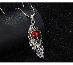 Détail du collier plume vintage avec pierre œil de démon rouge sur socle noir texturé