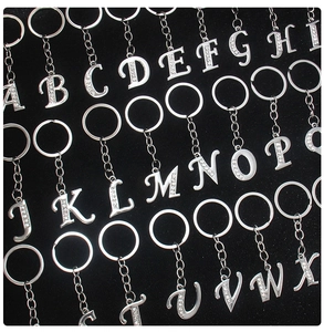 Detailed close-up of 26 silver alphabet keychains with rhinestones on black velvet