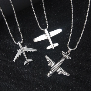 Detalle de tres colgantes de avión en acero inoxidable con cadenas de bolas finas