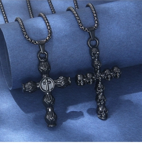 Close-up of matte black stainless steel cross and skull pendant necklace on blue paper