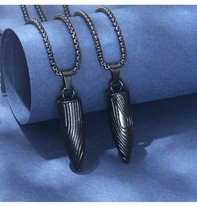 Détail de pendentifs balles noir mat avec texture grain de bois sur chaîne en acier