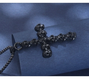 Close-up of gothic black skull cross pendant with beaded chain on textured blue background