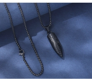 Détail macro du pendentif balle en acier inoxydable noir avec motif et chaîne de boîte