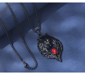Detail of black wolf head pendant with vibrant red gemstone on textured dark background
