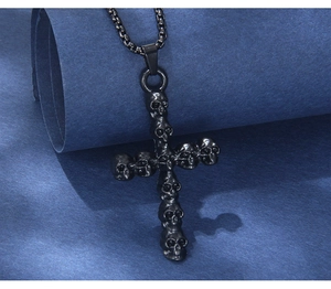Detailed close-up of gothic black stainless steel skull cross pendant on textured surface