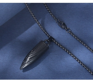 Gros plan du pendentif balle noire à texture spirale avec sa chaîne boîte assortie