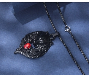 Close-up of black gothic wolf head pendant with red gemstone on a dark chain