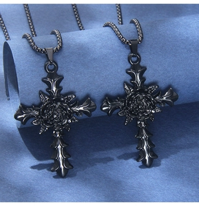 Close-up of gothic black cross necklaces with rose detail on blue background