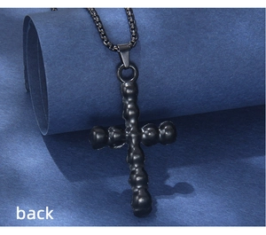 Detail view of the back of a black beaded texture cross pendant on a thin box chain