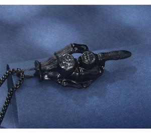 Macro detail of matte black skull hand pendant with EMO engraving on beaded chain