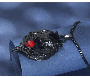 Macro shot of gothic black wolf head pendant with red gemstone and metal ball chain