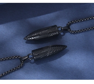 Vue macro de pendentifs balles noir mat avec texture spirale et chaîne box en métal