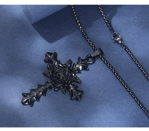 Macro view of gothic black stainless steel cross necklace with central rose detail