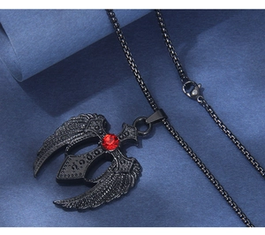 Gros plan du collier croix gothique avec ailes et strass rouge sur papier bleu