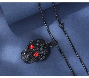 Détail d'un pendentif crâne gothique noir avec yeux en strass rouges sur une chaîne
