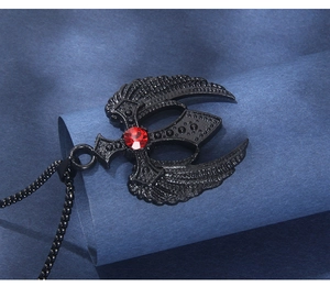Vue macro du pendentif croix gothique ailé avec strass rouge sur chaîne à billes noire