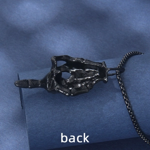 Back view of black hip-hop skull hand middle finger pendant on dark textured background