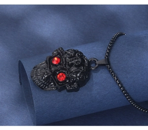 Détail du pendentif crâne noir mat avec yeux en cristal rouge et chaîne à billes