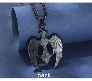 Détail de l'arrière texturé d'un pendentif ailes noires avec une chaîne à mailles carrées