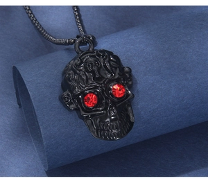 Détail du pendentif crâne noir gothique aux yeux en cristal rouge sur fond bleu