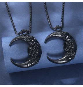 Macro shot of two black crescent moon pendants with rose floral relief on a metal chain