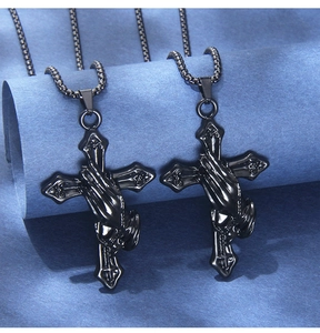 Macro detail of gothic black stainless steel prayer hands cross pendant on ball chain