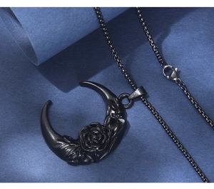 Macro detail of gothic black crescent moon necklace with intricate rose engraving