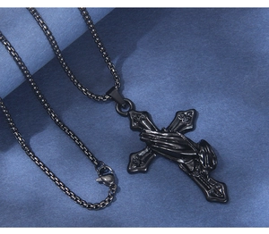 Detail of black stainless steel cross necklace featuring praying hands relief on box chain