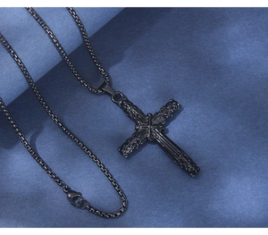 Gros plan du pendentif croix en acier inoxydable noir avec texture de relief gothique