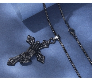 Macro view of black stainless steel cross necklace with praying hands relief and box chain