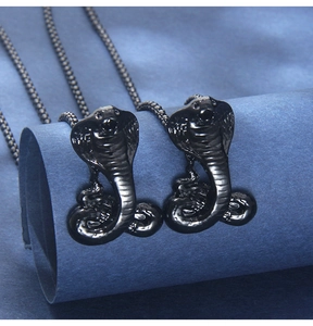 Detail of a black mamba cobra pendant with textured scales on a blue paper backdrop