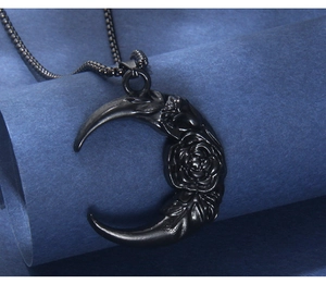 Macro shot of black crescent moon pendant with rose relief on matching metal box chain