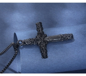 Détail du pendentif croix noire gothique avec textures en relief et chaîne en métal