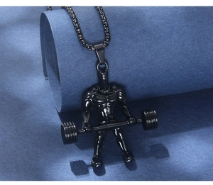 Vue détaillée du pendentif haltérophile noir poli sur fond de papier texturé bleu