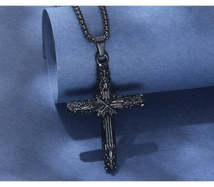 Détail du pendentif croix noire en acier inoxydable avec des motifs punk gravés