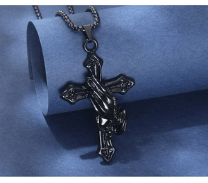 Macro detail of black stainless steel cross pendant featuring 3D praying hands relief