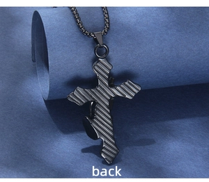 Macro detail of the matte black stainless steel cross pendant featuring vertical texture