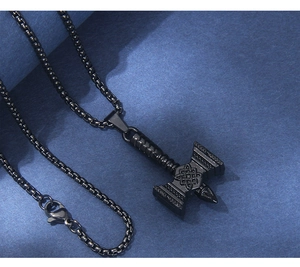 Macro detail of black Mjölnir hammer pendant with Nordic patterns and steel box chain