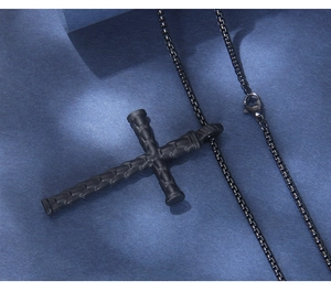 Macro detail of industrial black cross necklace with matte bone-textured pendant and box chain