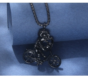 Macro shot of black stainless steel biker skull pendant and box chain on textured blue paper