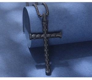 Macro shot of black matte cross pendant featuring unique industrial scale texture and box chain