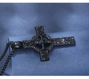 Gros plan d'un pendentif croix celtique noire polie avec textures entrelacées