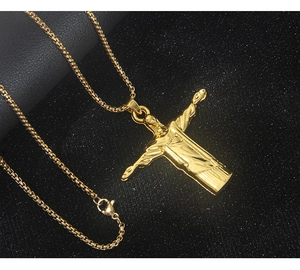 Vue macro du pendentif Jésus doré avec chaîne box sur un fond noir texturé
