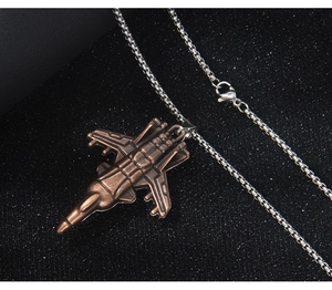 Gros plan d'un pendentif d'avion de chasse vintage avec texture métallique sur chaîne argent