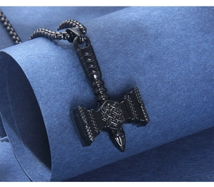 Macro shot of matte black Mjolnir pendant with Celtic patterns and textured metal chain